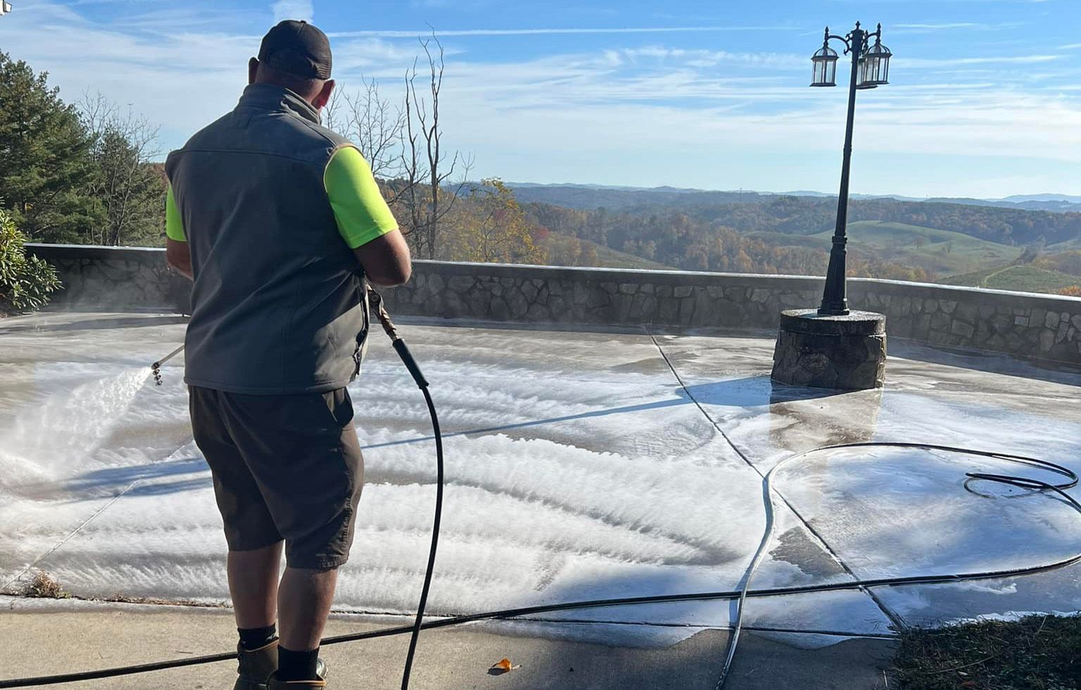 Washing a wide concrete terrace with the ridgeline layered behind it