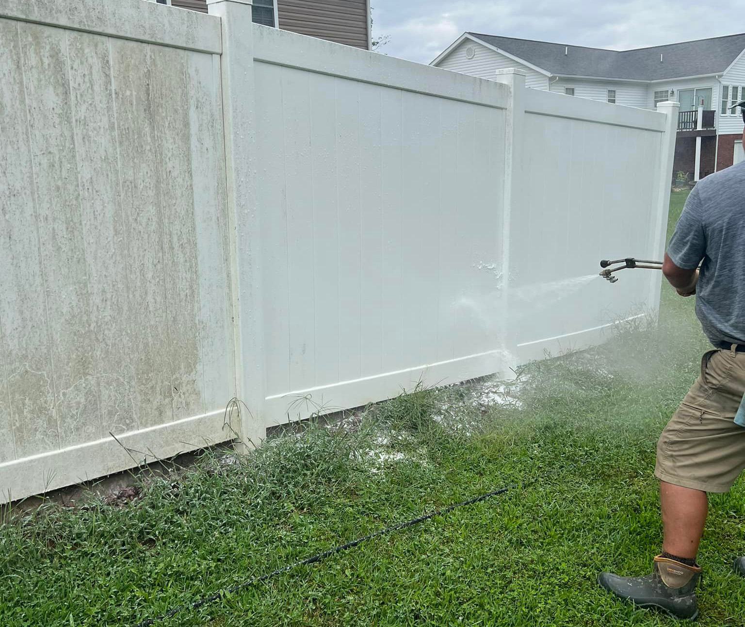 Washing a white vinyl fence with a hard clean against algae split line running down the panel
