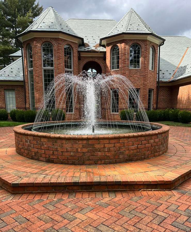 A brick fountain running in front of a large brick building on a clean paver plaza